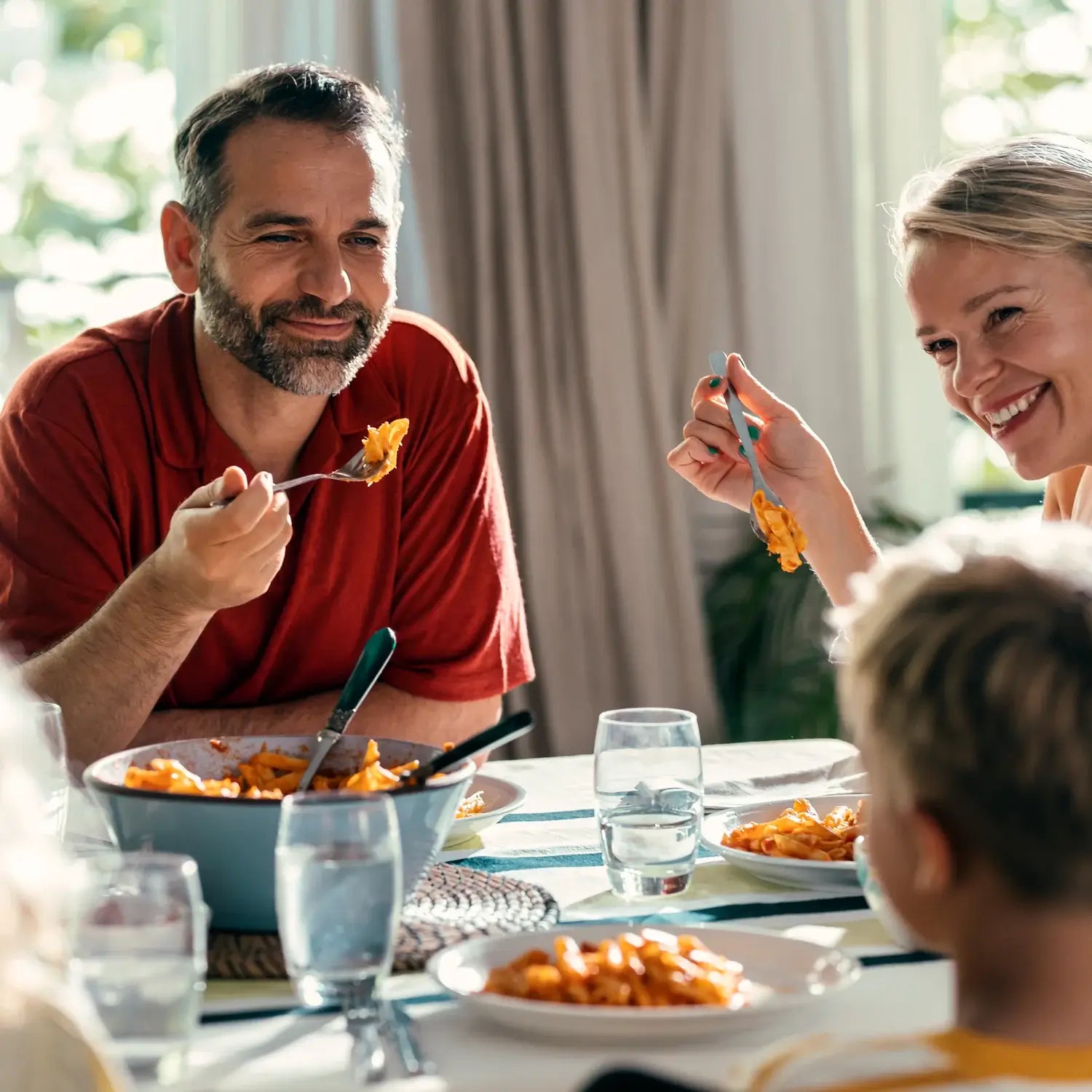 Family smiling and eating pasta dinner